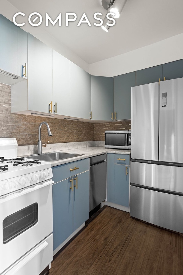 kitchen featuring blue cabinetry, dark wood finished floors, light countertops, appliances with stainless steel finishes, and a sink