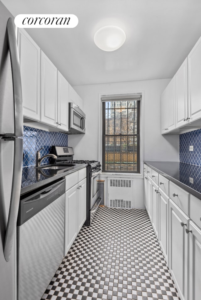 30 E 9th St Unit 1D, New York City, NY 10003 - kitchen with radiator, stainless steel appliances, white cabinets, and dark countertops