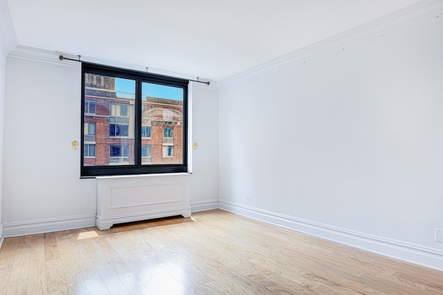 empty room with crown molding, baseboards, and wood finished floors