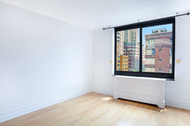 unfurnished room featuring crown molding, wood finished floors, and baseboards