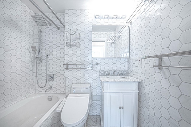 full bathroom featuring toilet, vanity, tile walls, tiled shower / bath, and tile patterned floors