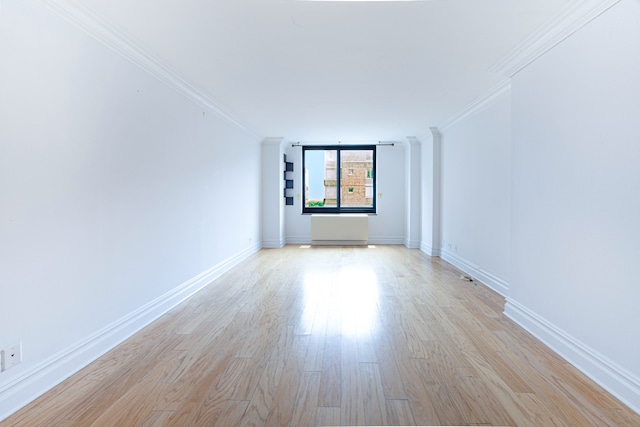 unfurnished room with ornamental molding, light wood-type flooring, and baseboards