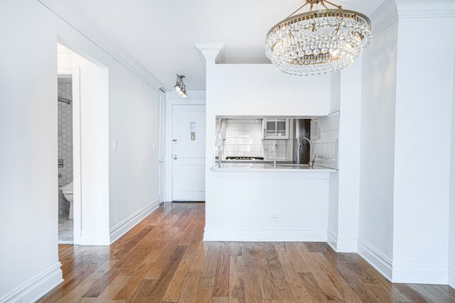 kitchen featuring sink, a chandelier, dark hardwood / wood-style flooring, decorative backsplash, and crown molding