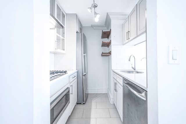 kitchen with tasteful backsplash, stainless steel appliances, a sink, and light countertops