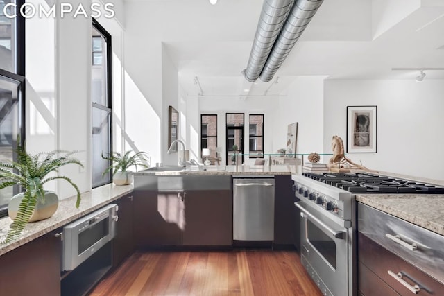 kitchen featuring stainless steel range, dark hardwood / wood-style flooring, dark brown cabinetry, and light stone countertops