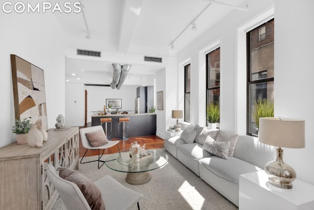 living room with wood-type flooring, beamed ceiling, and rail lighting