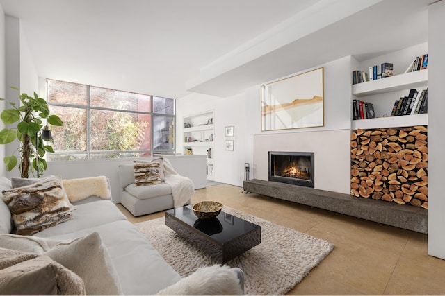 tiled living room featuring a lit fireplace and built in shelves