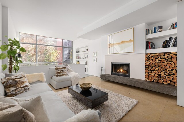 tiled living room featuring a lit fireplace and built in features