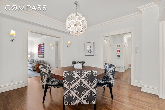 dining area featuring ornamental molding, wood finished floors, baseboards, and a chandelier