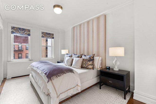 bedroom featuring ornamental molding, baseboards, and wood finished floors