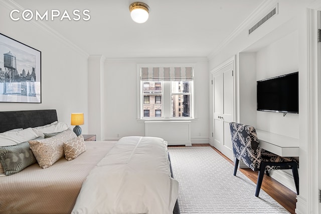 bedroom featuring crown molding, wood finished floors, radiator, and baseboards