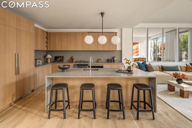 kitchen featuring hanging light fixtures, a breakfast bar, light wood-type flooring, and tasteful backsplash