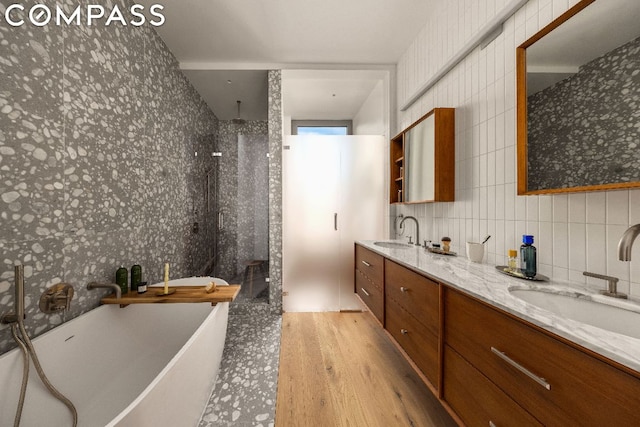 bathroom featuring hardwood / wood-style floors, vanity, tasteful backsplash, a shower, and tile walls