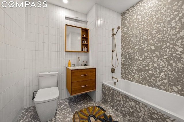 full bathroom featuring tile walls, tiled shower / bath combo, vanity, and toilet