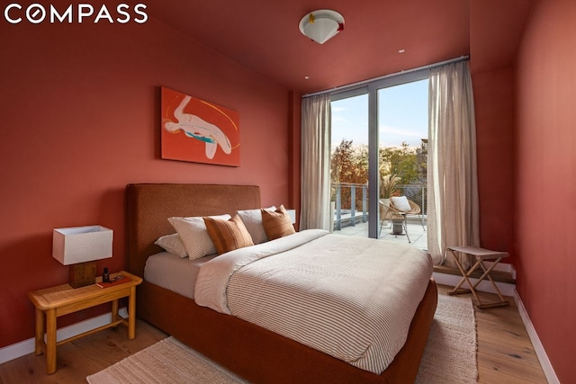 bedroom featuring access to outside, floor to ceiling windows, and hardwood / wood-style floors