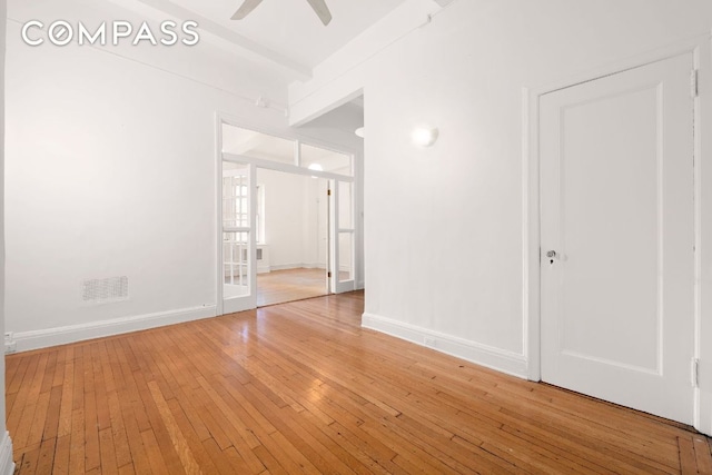 spare room with beamed ceiling, hardwood / wood-style floors, and ceiling fan