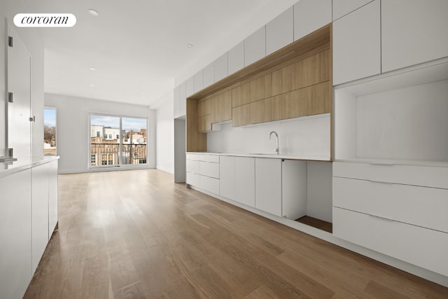 unfurnished living room featuring sink and light hardwood / wood-style floors