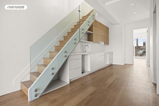 stairs with hardwood / wood-style flooring and sink