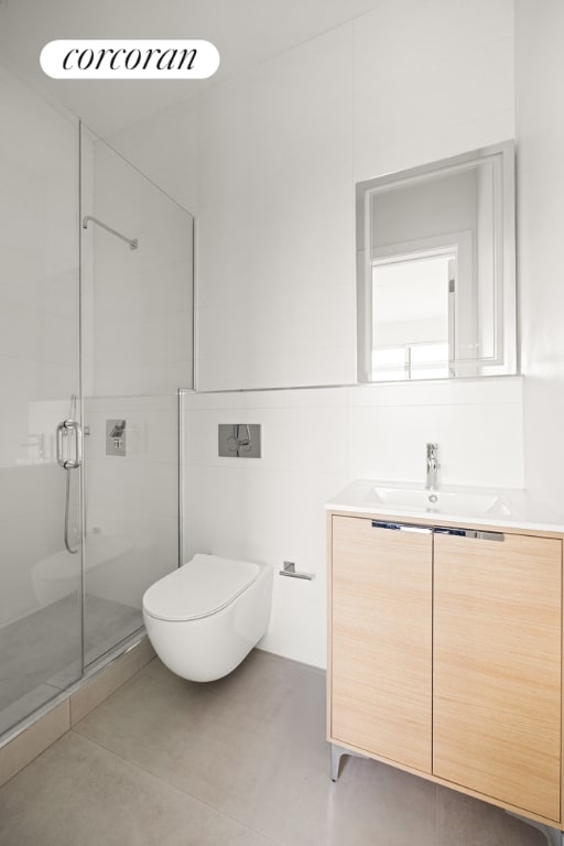 bathroom featuring toilet, tile walls, vanity, and a shower with door