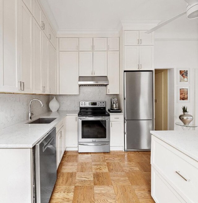 kitchen featuring white cabinets, appliances with stainless steel finishes, tasteful backsplash, sink, and light stone counters