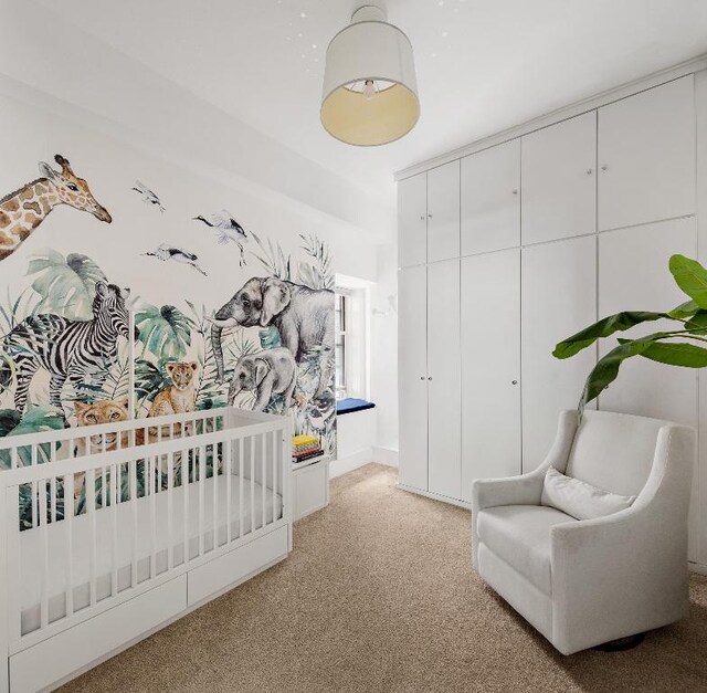 bedroom with a closet, light colored carpet, and a nursery area