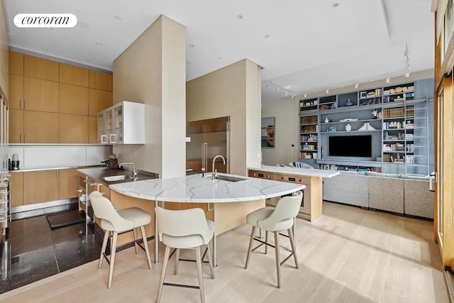 kitchen with built in refrigerator, a kitchen bar, sink, built in features, and kitchen peninsula