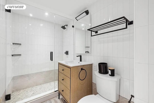 bathroom with tile walls, toilet, vanity, and walk in shower