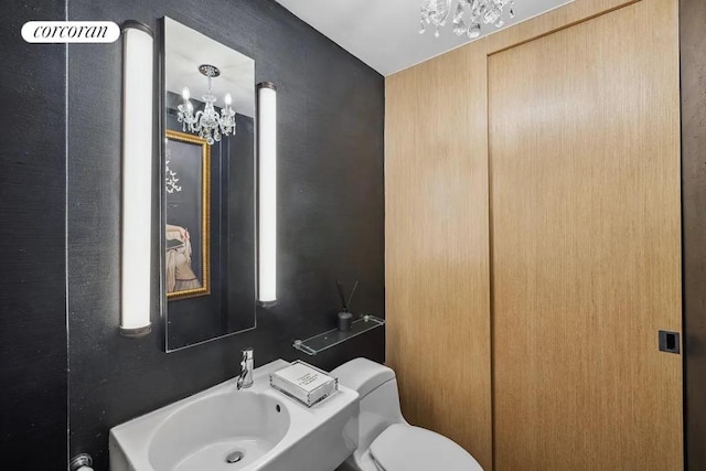 bathroom featuring toilet and a chandelier