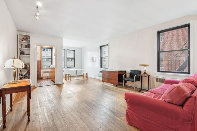 living area featuring radiator, baseboards, track lighting, and wood finished floors