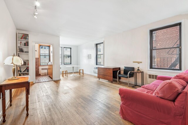 living room featuring track lighting, radiator heating unit, baseboards, and hardwood / wood-style floors