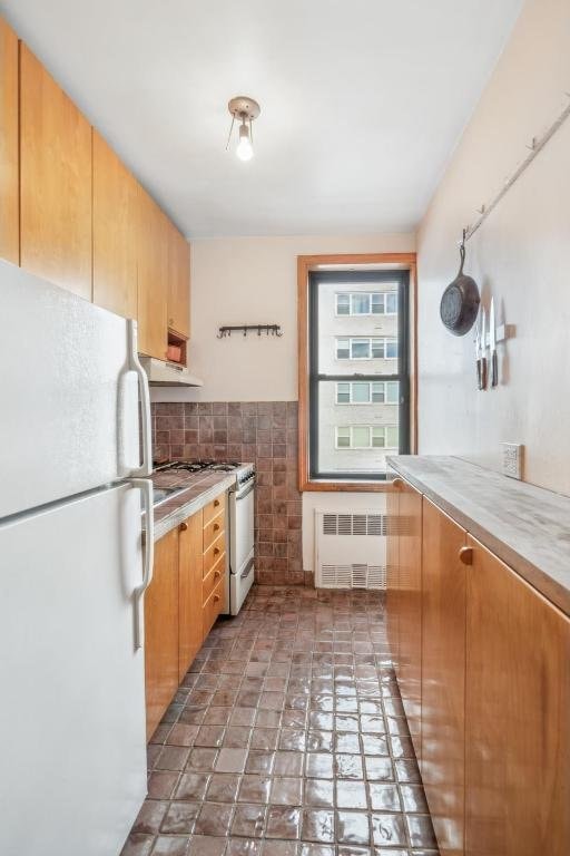 kitchen with tile walls, radiator heating unit, and white appliances