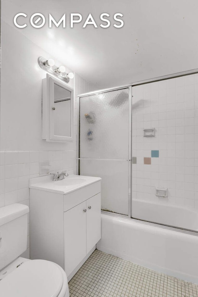 full bathroom featuring tile patterned flooring, vanity, toilet, enclosed tub / shower combo, and tile walls
