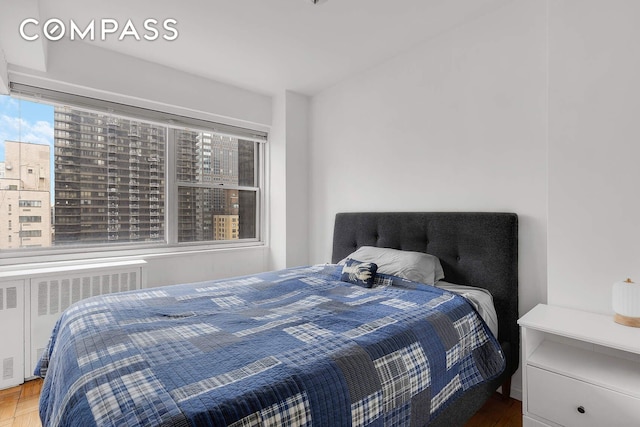 bedroom with radiator and wood finished floors