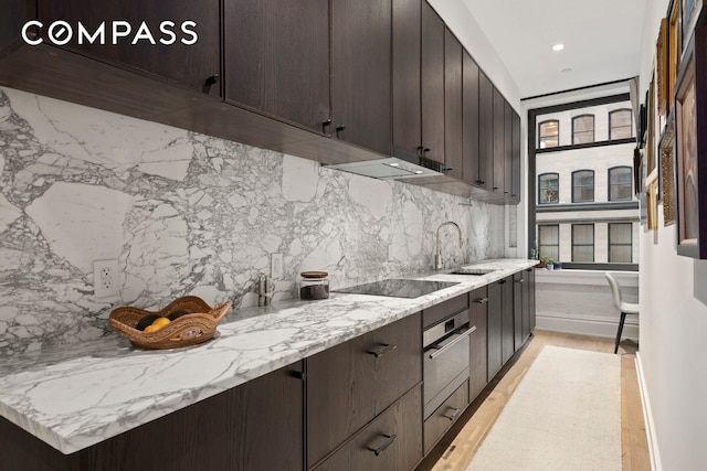 181 Hudson St Unit 2B, New York City, NY 10013 - kitchen featuring oven, black electric stovetop, tasteful backsplash, dark brown cabinets, and recessed lighting