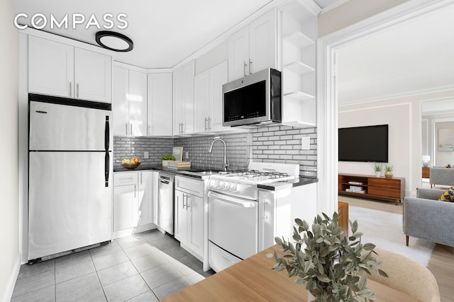 321 E 54th St Unit 10B, New York City, NY 10022 - kitchen featuring appliances with stainless steel finishes, a sink, white cabinetry, backsplash, and ornamental molding