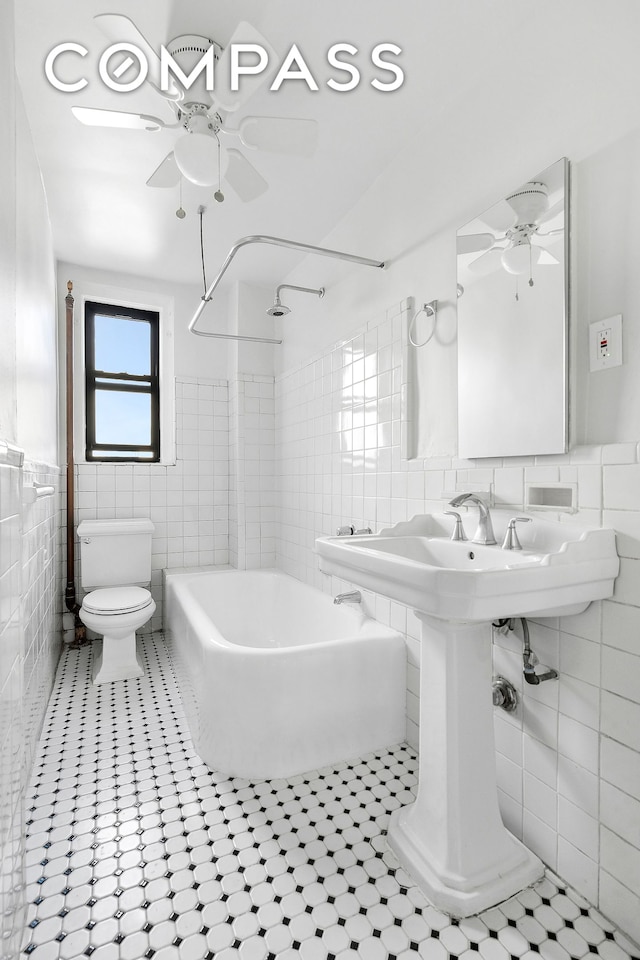 321 E 54th St Unit 10B, New York City, NY 10022 - full bathroom featuring tile walls, a ceiling fan, tub / shower combination, tile patterned floors, and wainscoting