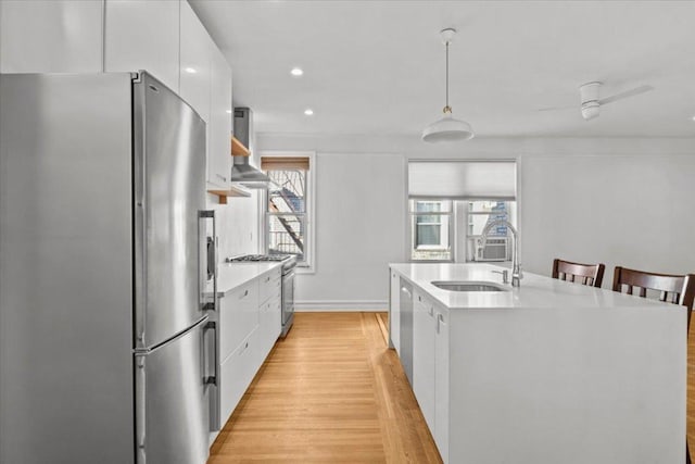 kitchen featuring stainless steel appliances, a sink, white cabinets, modern cabinets, and decorative light fixtures