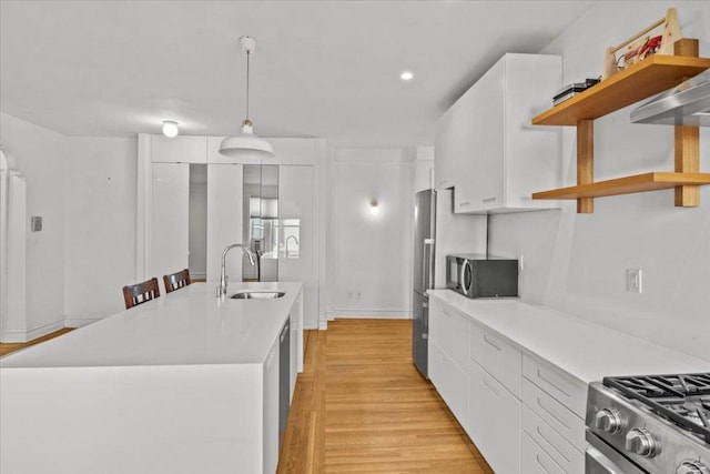 kitchen featuring decorative light fixtures, open shelves, light countertops, white cabinetry, and a sink