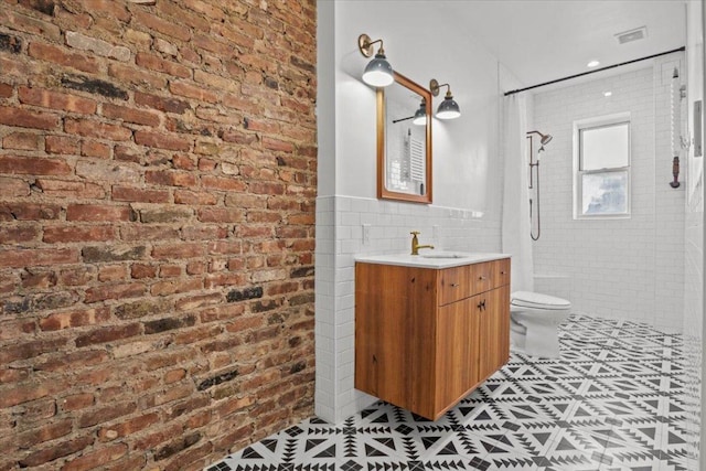 bathroom with toilet, curtained shower, tile patterned flooring, vanity, and tile walls