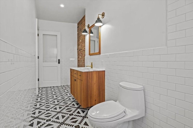 bathroom featuring tile patterned flooring, toilet, a wainscoted wall, vanity, and tile walls