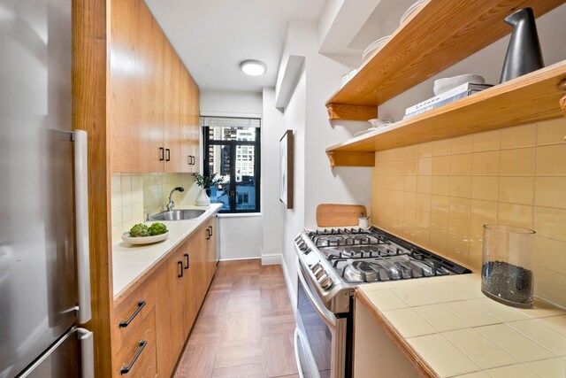 kitchen featuring tile countertops, stainless steel appliances, backsplash, dark parquet flooring, and sink