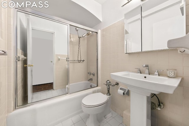 bathroom with bath / shower combo with glass door, tile walls, and tile patterned floors