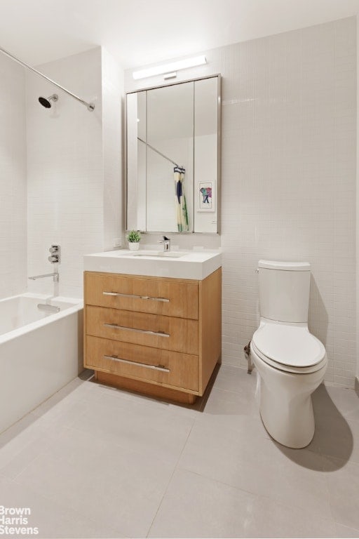 full bathroom with tile walls, tile patterned flooring, vanity, shower / bathing tub combination, and toilet