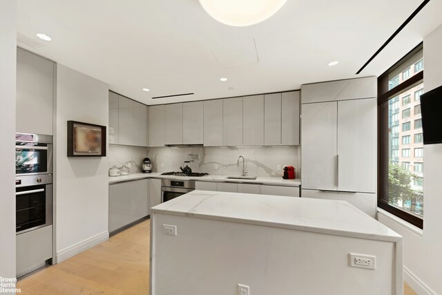 kitchen featuring backsplash, modern cabinets, gray cabinets, and a sink