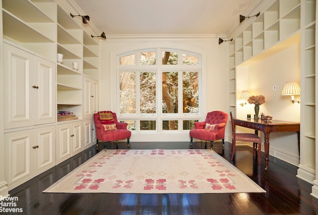 sitting room with ornamental molding, dark wood-type flooring, and built in shelves