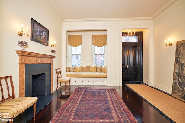 living area with dark wood-style floors, a fireplace with raised hearth, ornamental molding, a chandelier, and baseboards