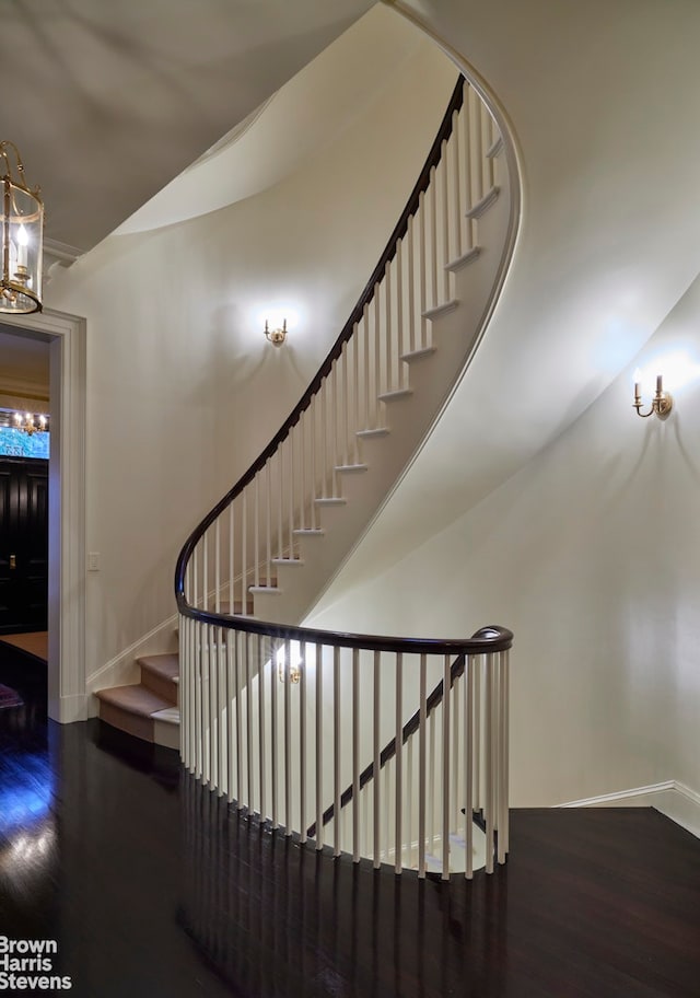 stairs featuring a notable chandelier, baseboards, and wood finished floors