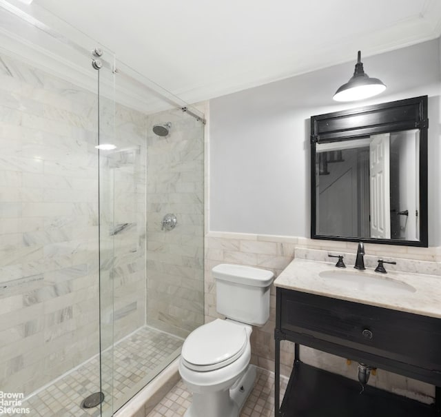 bathroom with toilet, tile walls, a shower with shower door, and vanity