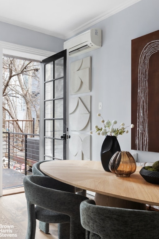 dining room featuring a wall unit AC, crown molding, and hardwood / wood-style floors