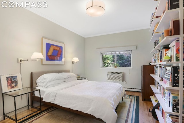 bedroom featuring wood-type flooring, a baseboard heating unit, a wall unit AC, and crown molding